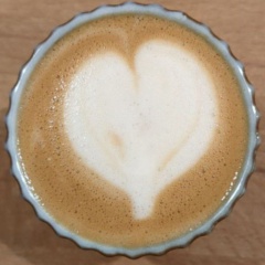 top down view of flat white coffee cup with milk art in a heart shape